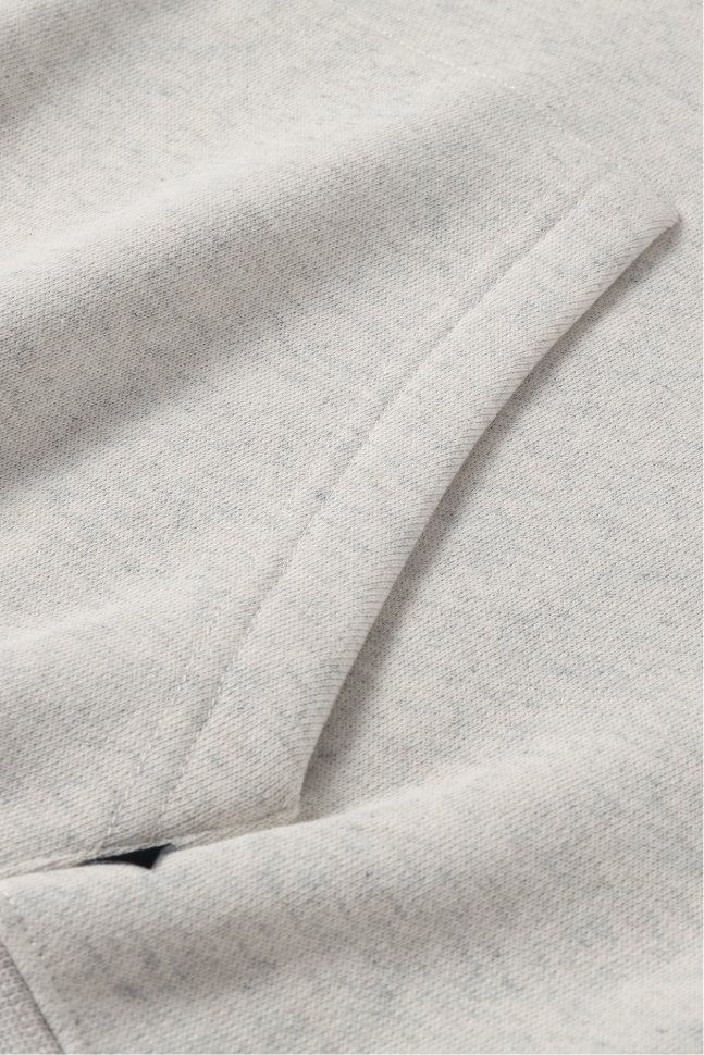 Close-up of the light heather grey hoodie's kangaroo pocket with visible stitching and heavyweight knit fabric.