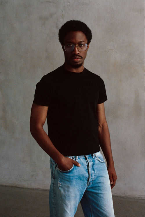 Model wearing a black crewneck short-sleeve T-shirt with light blue jeans.
