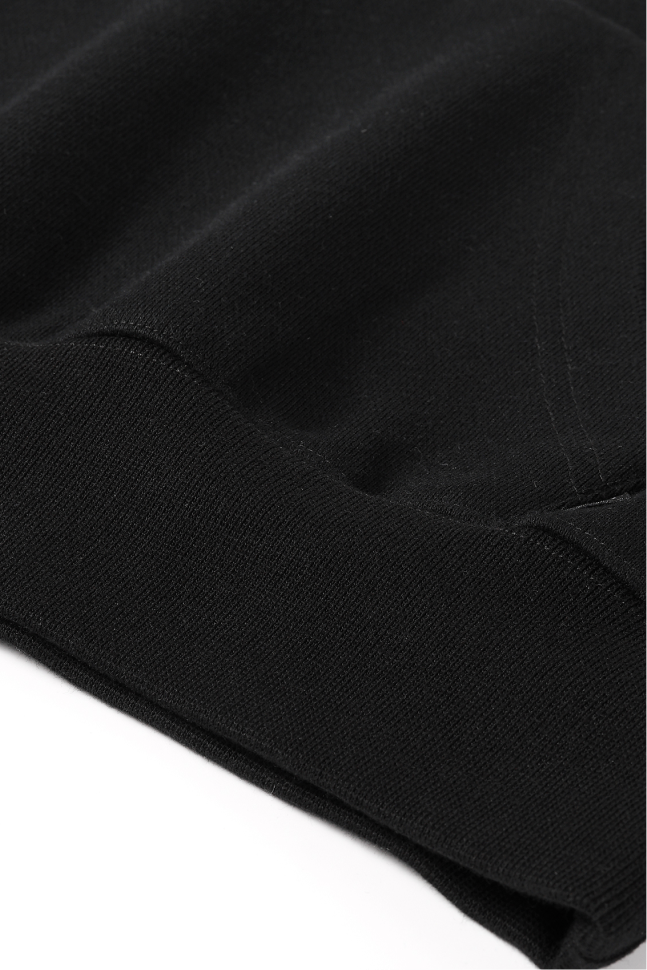 Close-up of the black hoodie's ribbed hem and smooth fabric.