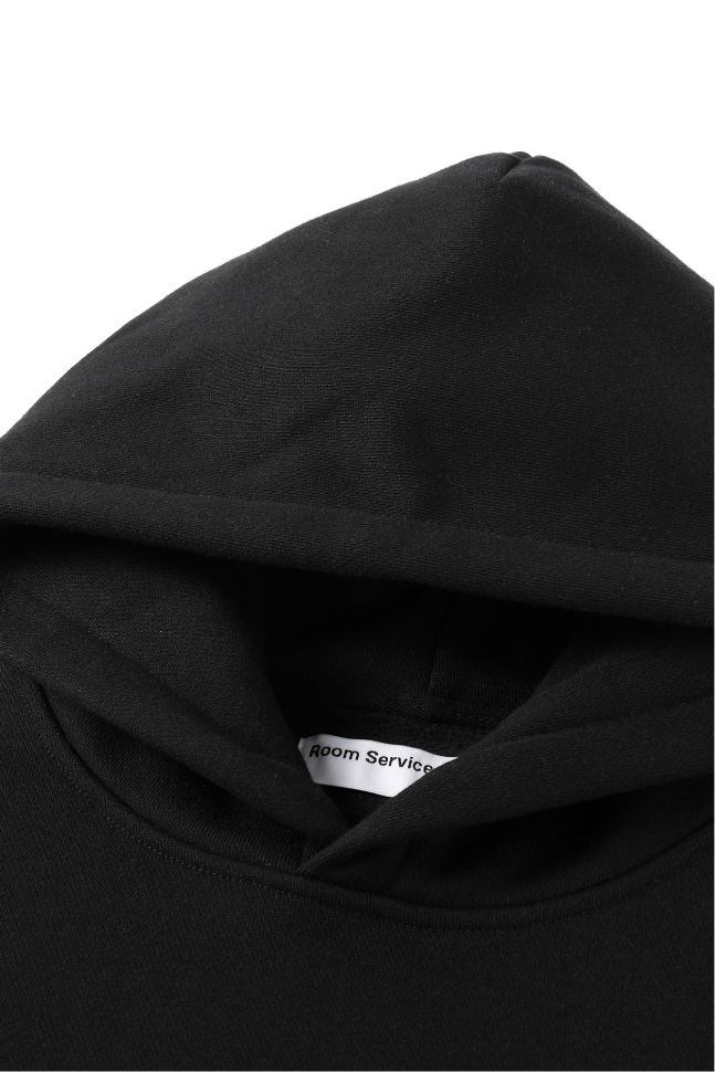 Close-up of the black hoodie featuring the fixed hood and front neckline.