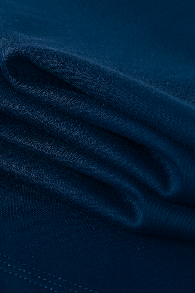 A close-up of folded dark navy blue fabric with a smooth texture and visible stitching along one edge.