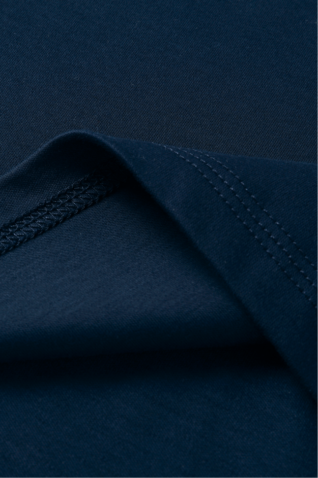Close-up of dark navy blue fabric with a folded corner showing stitched seam detail.